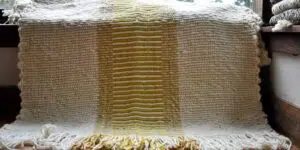 Alfombra tejida a telar en lana, imagen de alfombra blanca con un centro de lineas horizontales blancas y amarillas