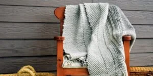 piecera telar, piecera, en tonos grises, extendida en un silla de madera, con un entorno acogedor